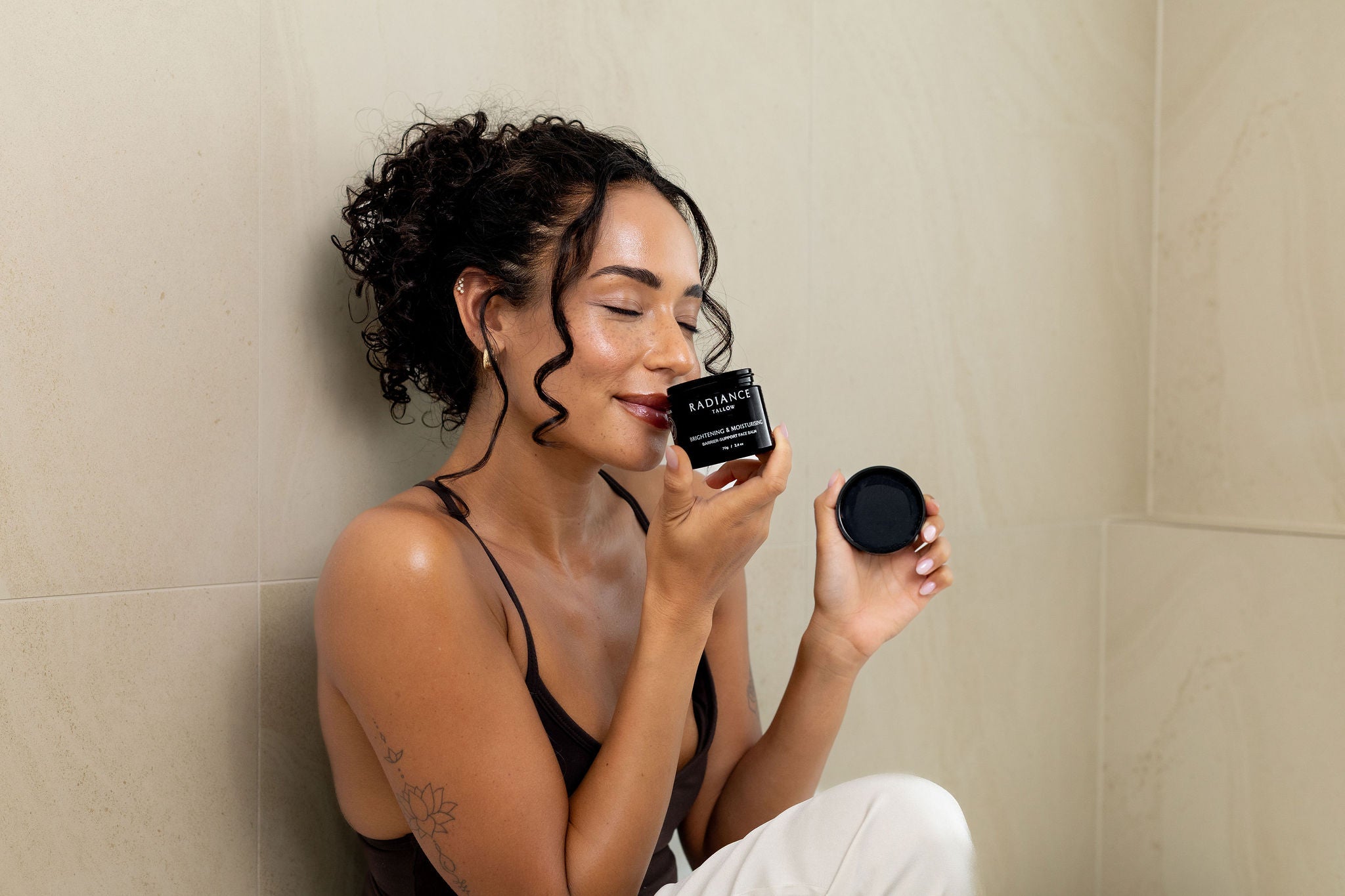 Woman holding a black container with a beige wall background